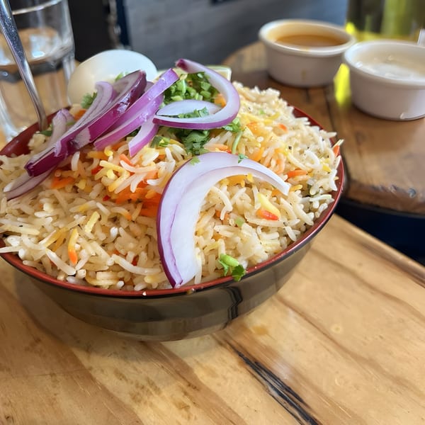 Aaha Indian Cuisine's biryani, topped with sliced red onions, cilantro, and a hard-boiled egg.